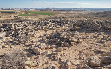 ancient atone ruins high on a hill above Kibbutz Sde Boker with the cliffs of the Nahal Zin stream and a blue sky background