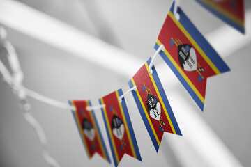 A garland of Swaziland national flags on an abstract blurred background