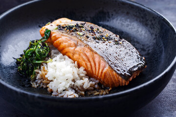 Traditional Japanese salmon fish teriyaki filet with koshihikari rice and fried leaf spinach served as close-up in a Nordic design bowl