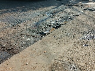 A hole in the damaged asphalt road