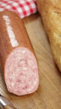 saucisson &agrave; l'ail et baguette de pain sur un planche &agrave; d&eacute;couper