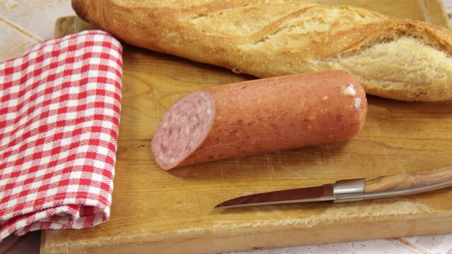 saucisson &agrave; l'ail et baguette de pain sur un planche &agrave; d&eacute;couper