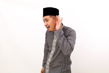 Obraz na płótnie Canvas Asian muslim man standing while holding his ear to listening something. Isolated on white background