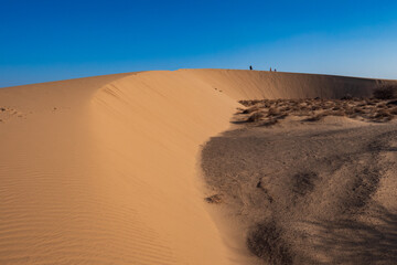 Fototapeta na wymiar A tourist standing on a beautiful sand dune at North Horr Sand Dunes in Marsabit County, Kenya
