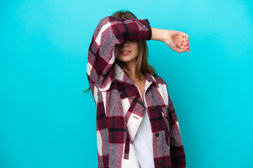 Young caucasian woman isolated on blue background covering eyes by hands