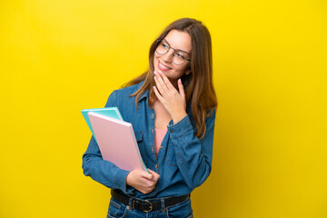 Young student caucasian woman isolated on yellow background looking up while smiling
