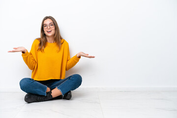 Young caucasian woman sitting on the floor isolated on white background with shocked facial expression