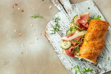 Homemade Spanish Ham Sandwich with arugula, cucumber, Tapas, antipasti on a wooden board. banner, menu, recipe place for text, top view