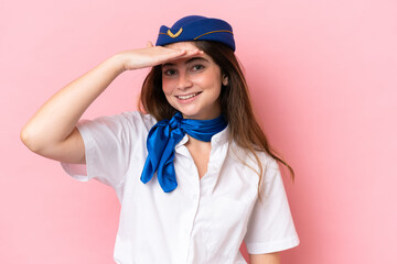 Airplane stewardess caucasian woman isolated on pink background looking far away with hand to look something