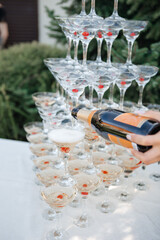 A bartender, a woman pours alcohol from a bottle, champagne into glasses.A waiter pours champagne into the glasses from the bottle in the restaurant. Catering service, banquet. official event.