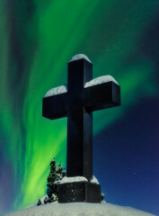 Historic crucifix in a cemetry at a night with polar lights