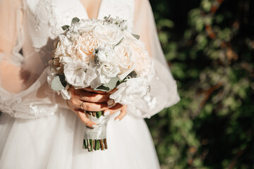 midsection of bride holding wedding bouquet. White flowers in woman hands.