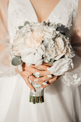midsection of bride holding wedding bouquet. White flowers in woman hands.