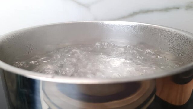 Pot with boiling water on stove in the kitchen. Slow motion