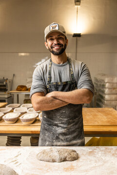 Bakers school, master baker kneading bread dough on table with flour, posing for portrait