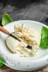 fresh soft white burrata cheese ball made from mozzarella and cream from Apulia, Italian Mediterranean cuisine, vertical image. top view. place for text