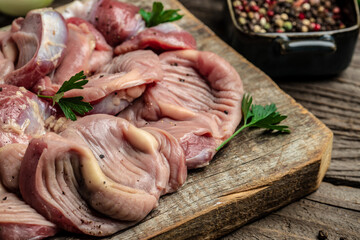 Raw uncooked chicken gizzards, stomach on a wooden background. Traditional Korean spicy chicken meat. Food recipe background. Close up