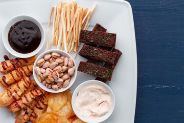 Beer snacks on the wooden table. Nuts, chips, pretzels.
