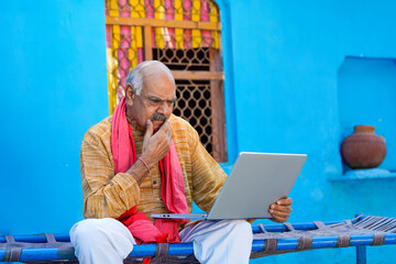 Indian farmer giving shocking expression after see in laptop - obrazy, fototapety, plakaty