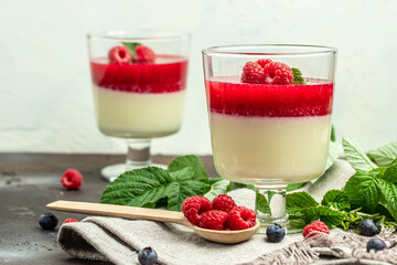 Raspberry Panna cotta with raspberry jelly on a dark background. Berry dessert with cream sauce in small jars. place for text