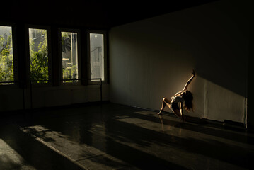 Golden lights shed on a dancer while practicing her moves alone