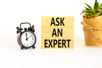 Ask an expert symbol. Concept words Ask an expert on wooden blocks on a beautiful white table white background. Black alarm clock. Business and ask an expert concept. Copy space.