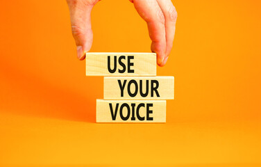 Use your voice symbol. Concept words Use your voice on wooden blocks on a beautiful orange table orange background. Businessman hand. Business and use your voice concept. Copy space.