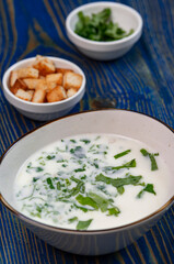 yogurt soup with herbs and crackers on a blue wooden table