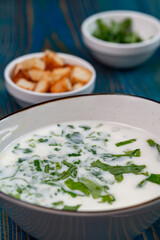 yogurt soup with herbs and crackers on a blue wooden table