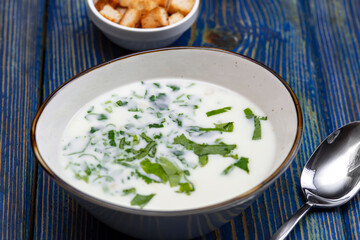 yogurt soup with herbs and crackers on a blue wooden table