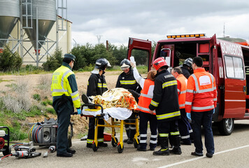 Victim of a traffic accident is attended by public emergency services with firefighters, paramedics...