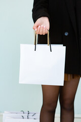 White empty papper bags in hand of young pretty woman doing shopping in casual style black clothes
