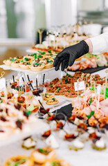 woman hands of a waiter prepare food for a buffet table in a restaurant