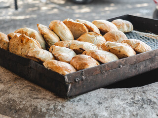 Fresh, hot buns lying on a tray near the hot stove. Sunny, clear day. Close-up, outdoors, no people. Tasty and healthy food concept
