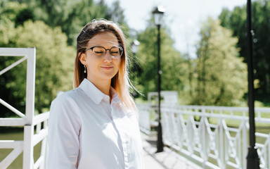 Portrait of cute caucasian young woman wearing glasses with closed eyes enjoying serenity outdoors