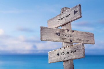 never lose control text quote on wooden signpost crossroad by the sea