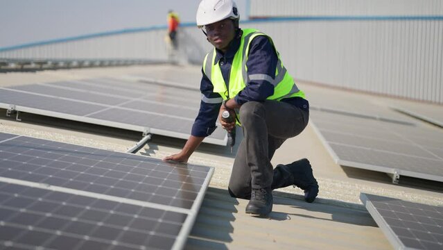 Engineer on rooftop sitting next to solar panels photo voltaic check alignment for good installation
