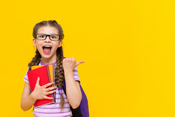 A schoolgirl with a briefcase and books on a yellow background points aside at your ad.