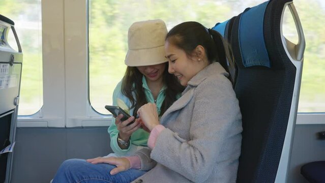 Asian woman tourist enjoy and fun outdoor lifestyle travel Japan by railway transportation on autumn holiday vacation. Attractive girl friends using mobile taking selfie together while travel on train