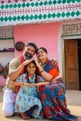 Happy Indian farmer with wife and daughter making home shape with hand. dream home concept.