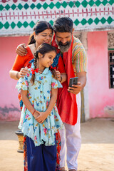 Fototapeta na wymiar indian farmer couple showing some detail to daughter in smartphone.