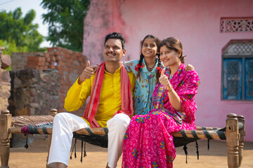 Fototapeta na wymiar Happy indian farmer couple showing thumps up with Daughter