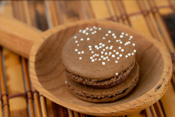 Chocolate macron served on a wooden spoon. High-quality photo with natural wood background