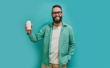 Smiling man holding a jar of medicine pills, daily vitamins and supplements. Health