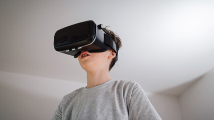 Caucasian male child putting on a virtual reality headset, looking surprised and amazed with a virtual world