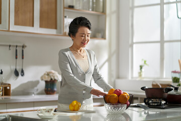 asian elderly woman standing in modern kitchen at home