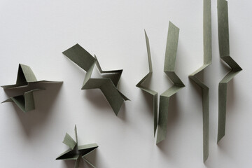 folded and cut green paper card objects viewed from above on blank paper
