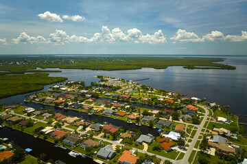 Aerial view of residential suburbs with one storey houses located near wildlife wetlands with green tropical vegetation on sea shore. Living close to nature in warm climate concept