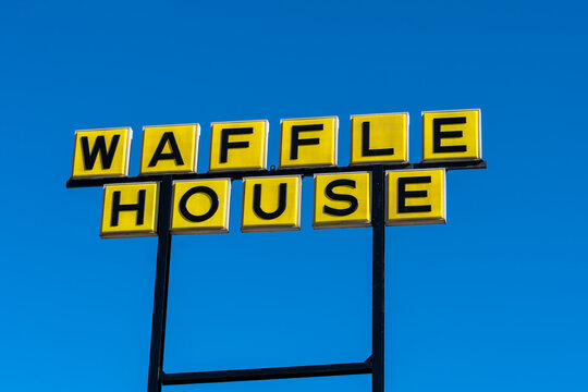 Lafayette, LA, USA - February 13, 2022: A Waffle House pole sign with blue sky in background. Waffle House is an American restaurant chain. 