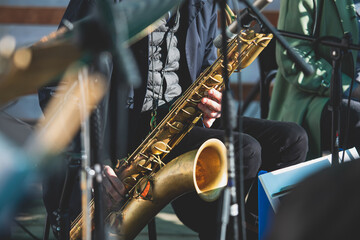 Fototapeta premium Concert view of saxophonist, a saxophone sax player with vocalist and musical band during jazz orchestra show performing music on stage in the scene lights